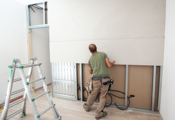 A worker installing drywall in a new home.